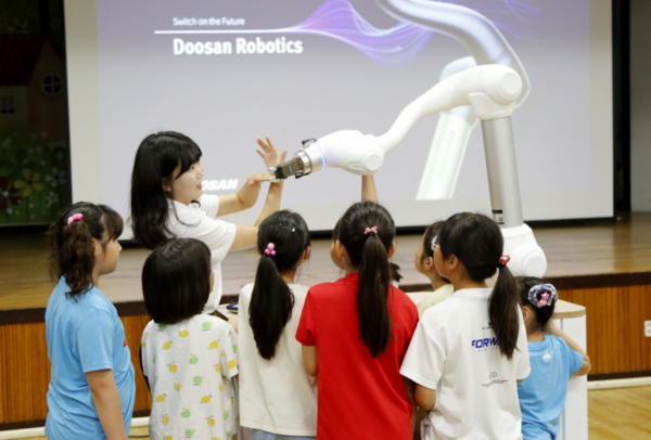 두산로보틱스 임직원이 아이들에게 협동로봇의 개념과 기본적인 작동 과정 등을 교육하고 있다. © 두산로보틱스