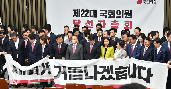 국민의힘 윤재옥 원내대표를 비롯한 당 지도부와 당선자들이 22일 오전 여의도 국회에서 두번째로 열린 당선자 총회에 참석해 행사시작 전 현수막을 펼쳐 보이고 있다.   ⓒ민주신문 김현수 기자