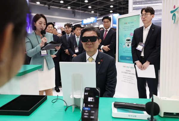 이억원 금융위원장이 26일 오전 서울 서초구 aT센터에서 열린 '코리아 핀테크 위크 2025' 하나금융 부스에서 AI 안경을 착용한 채 금융 상품 설명을 듣고 있다. ⓒ 뉴시스